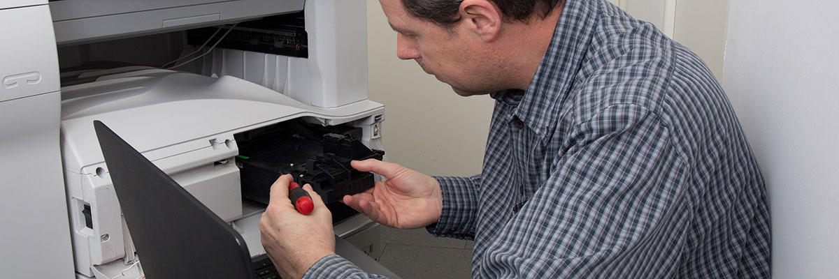 En tekniker reparerar en kopieringsmaskin.